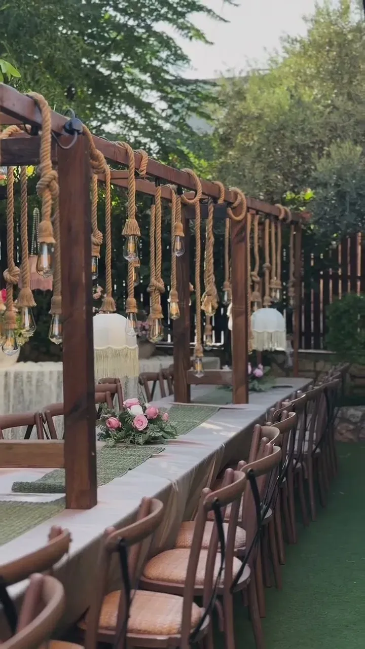שורת כיסאות עץ לאורך שולחן ערוך במתחם אירוח בחצר
